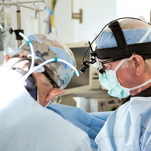 Two heart doctors in blue scrubs perform a procedure in the operating room