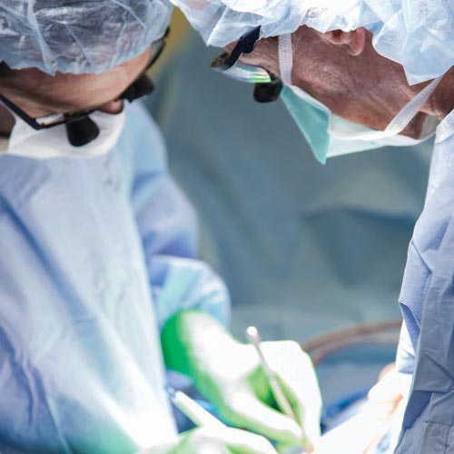 Two heart doctors in blue scrubs perform a procedure in the operating room