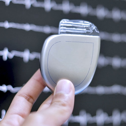 A close-up of a hand holding a silver heart failure device