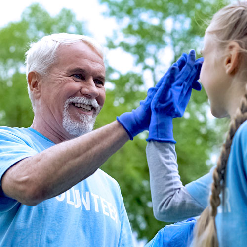 An older man wearing blue gloves and a blue shirt that says 